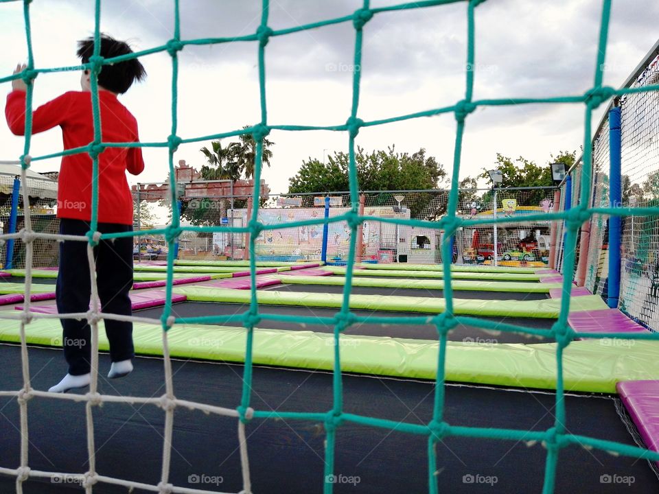 a child jumping on an elastic trampoline
