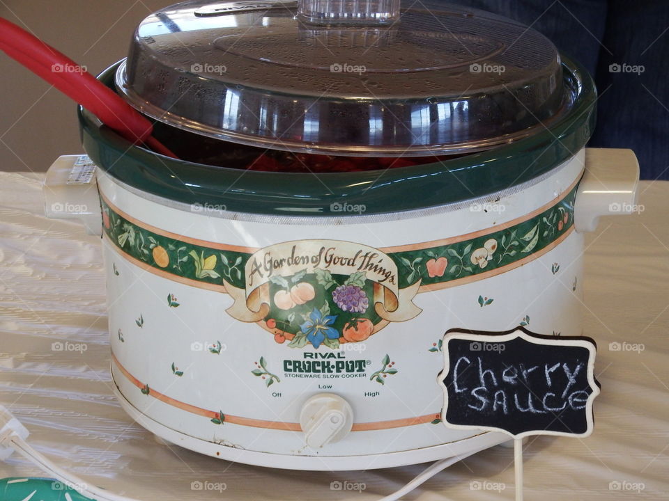 Decorative crock pot with cherry sauce.