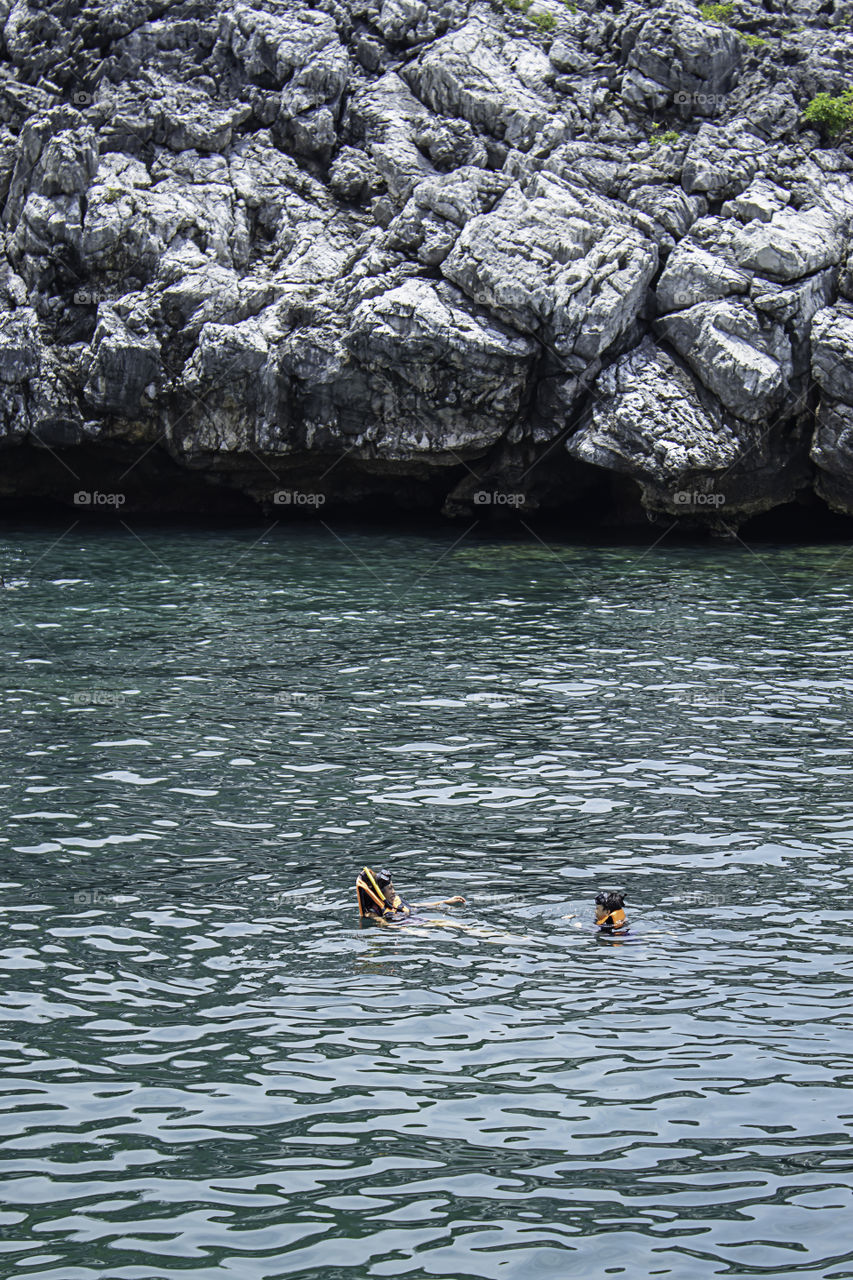 Mother and son wearing a life jacket, scuba diving in the sea.