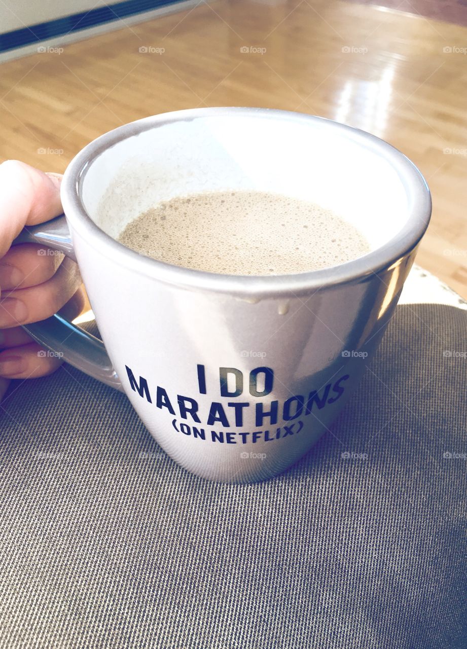 Frothy Bulletproof coffee in grey mug with cheeky saying  “I Do Marathons(on Netflix)”