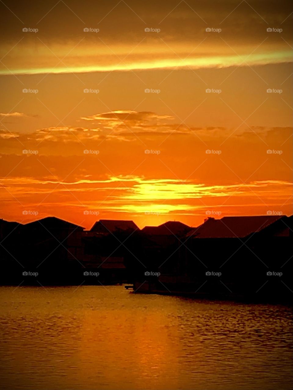 Sunset at the bay house with a bright orange and yellow sky against the silhouette of bay houses 