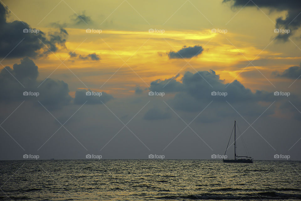 Yacht parked in the sea and the sun behind the clouds in the evening.