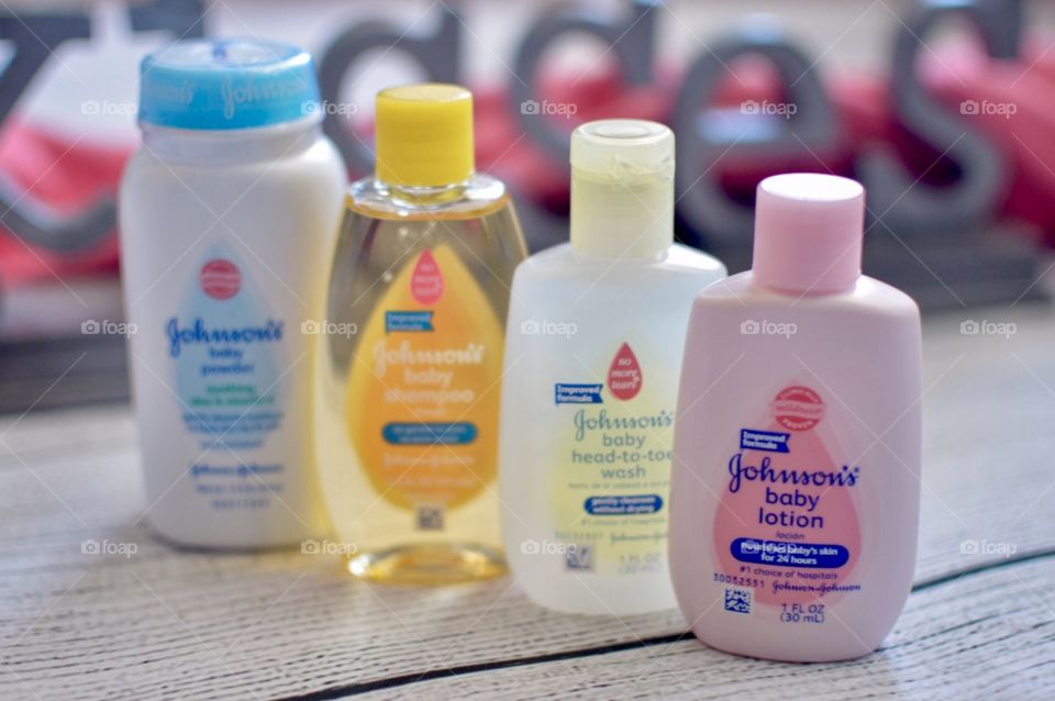 Johnson and Johnson baby products on a white rustic background with the word kisses in the back in a pink towel