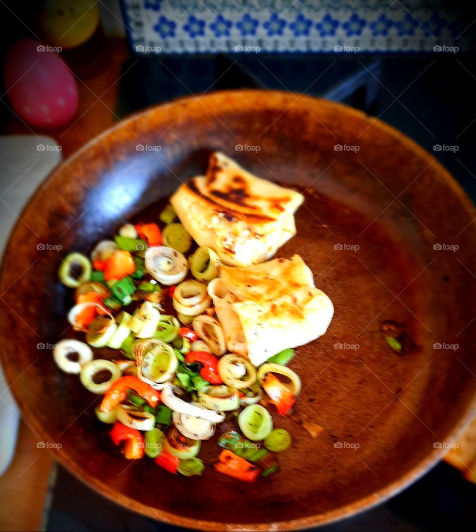 pancakes on a pan with  green leak and red pepper