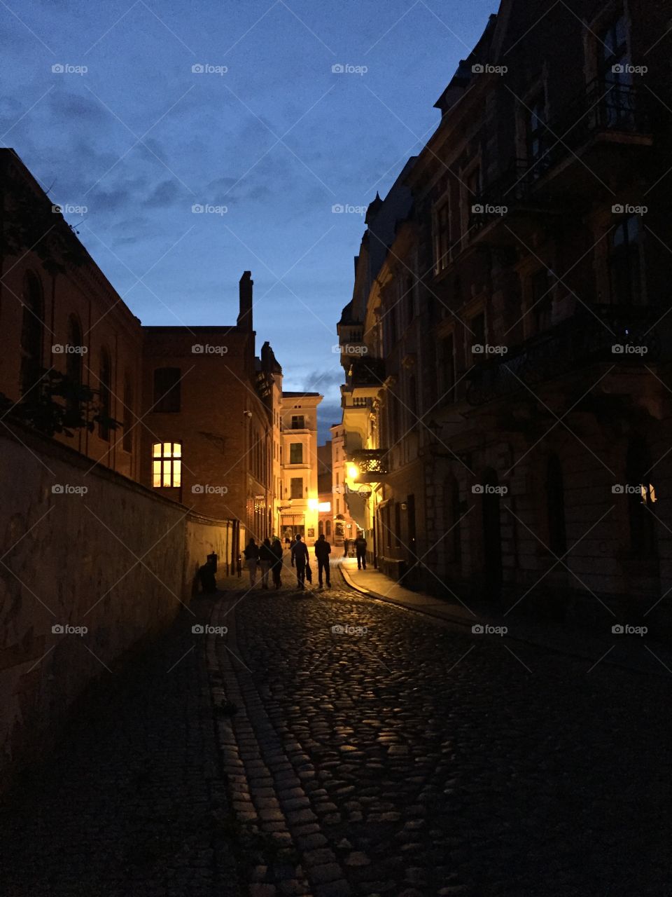 People shadowe in the streets of Torun in the evening lights