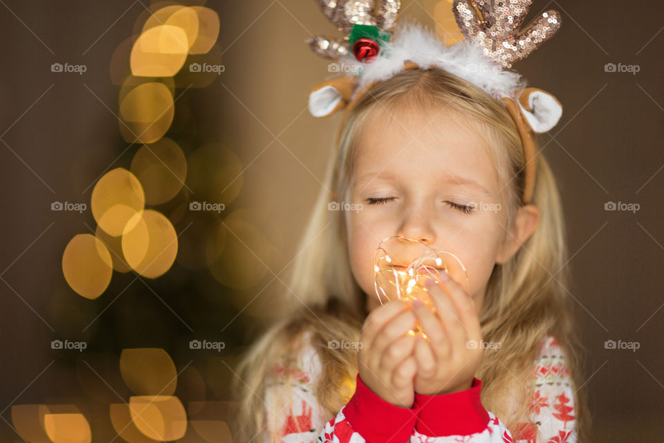 Cute little girl with blonde hair holding garland 