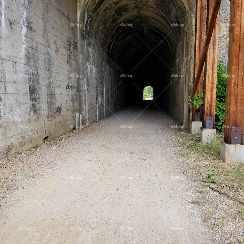 opening of an old railroad tunnel in the mountains with an opening at the end