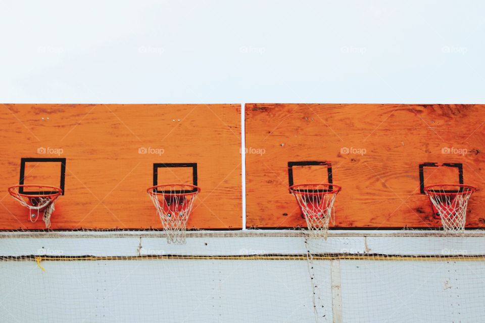 Basketball hoops with nets on weathered, orange, playwood backboards