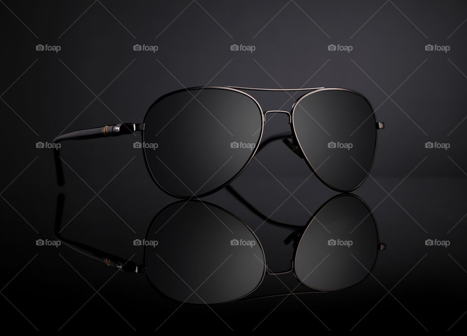 Aviator sunglasses on black background with reflection