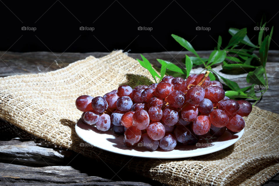 Red grapes on wooden board background.