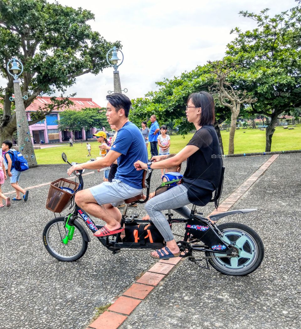 staying in good shape: riding tandem bike in the riverside park.