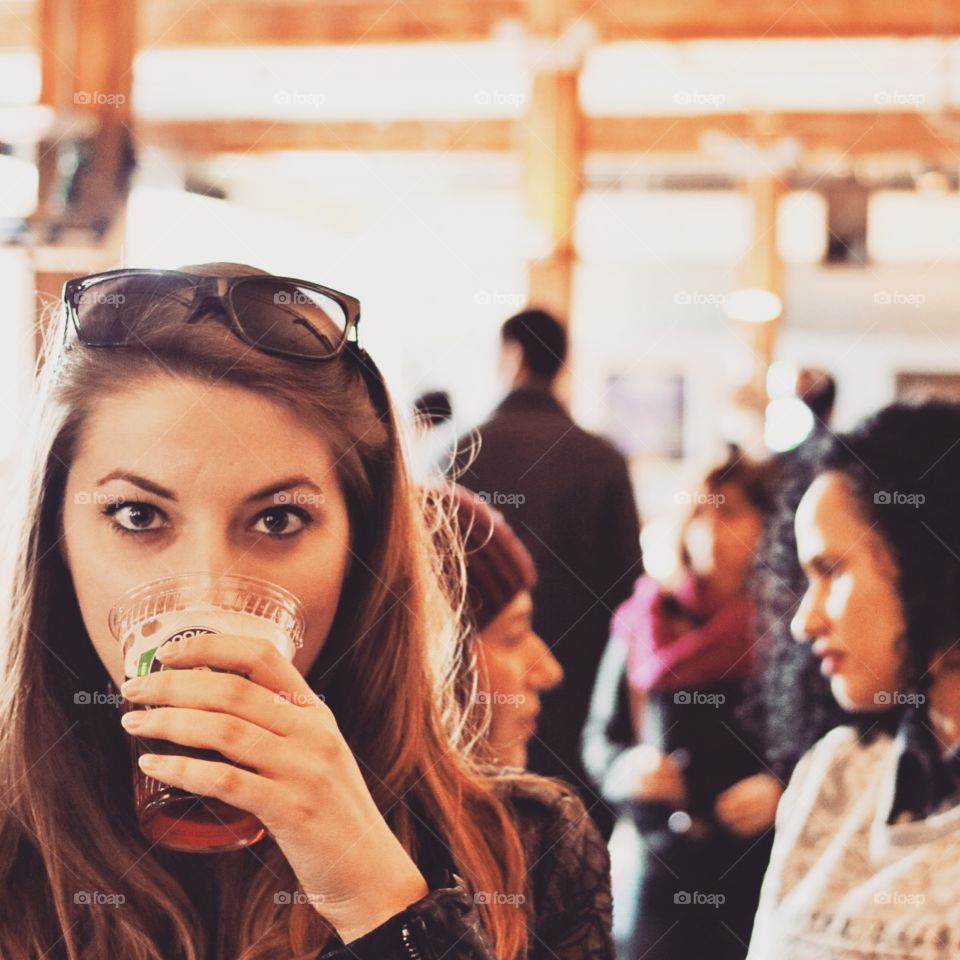 Girl drinking beer out of plastic cup. 