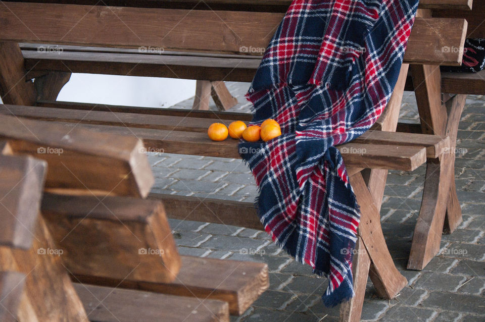 wooden bench, which has a blanket and tangerines