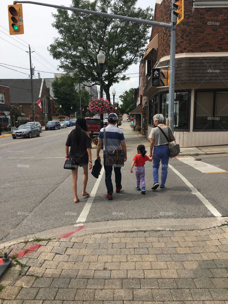 A family of four crossing a street in a town. 