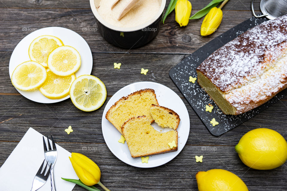 lemon cake on a plate, lemons, yellow tulips and decoration
