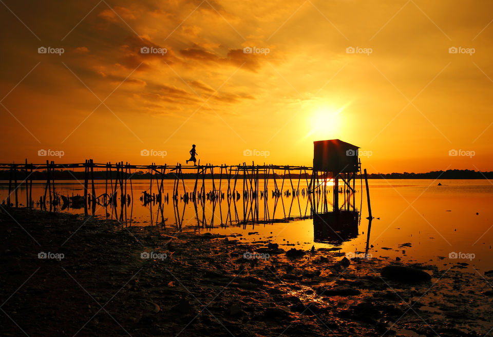 Silhouette of bridge over sea at sunset