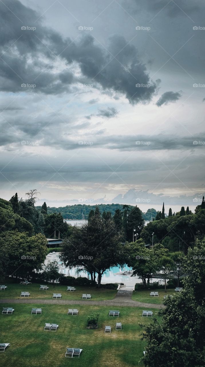 Storm clouds over a swimming pool and empty sun beds in Rovinj, Croatia