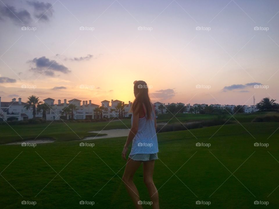 Women walking on golf course as the sunsets