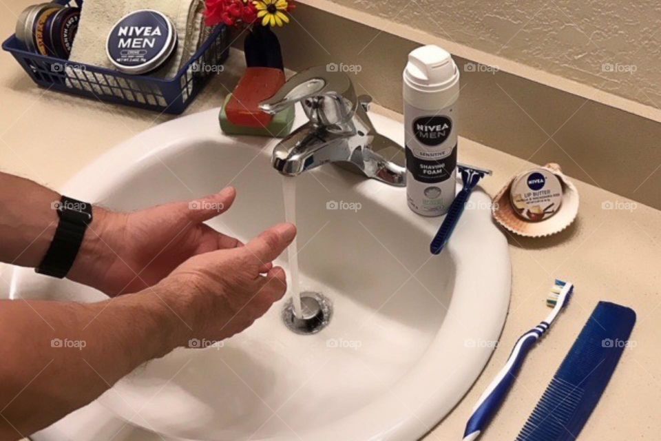 Man at the sink preparing his products for shaving.