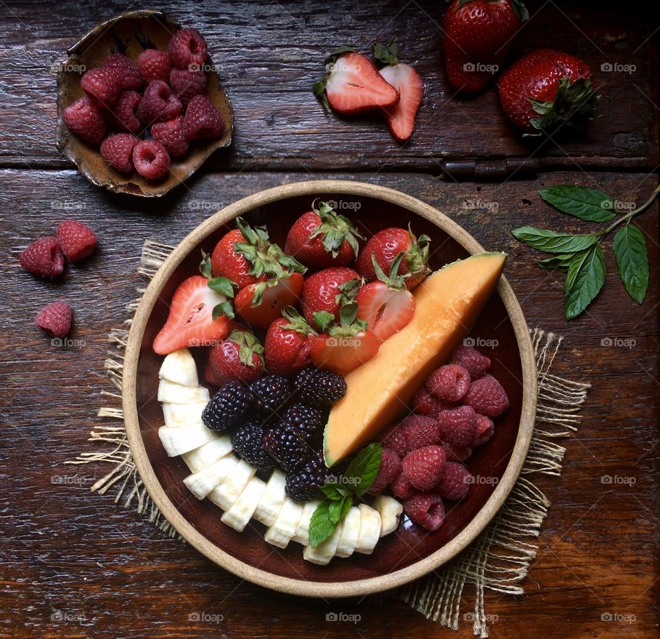Fresh fruit on plate sitting on a rustic wood table.
