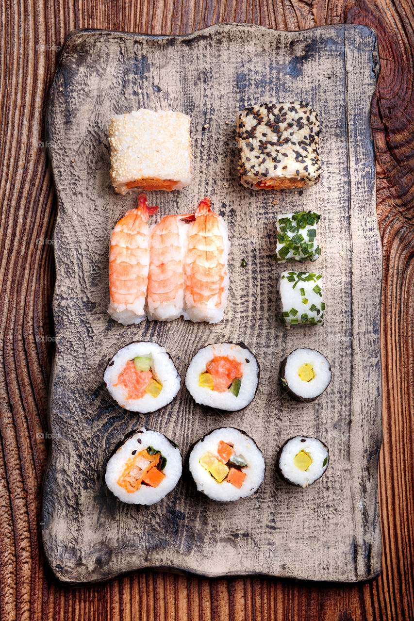 Sushi set on pottery plate with chopsticks and soy sauce in bowl on old wooden table from above