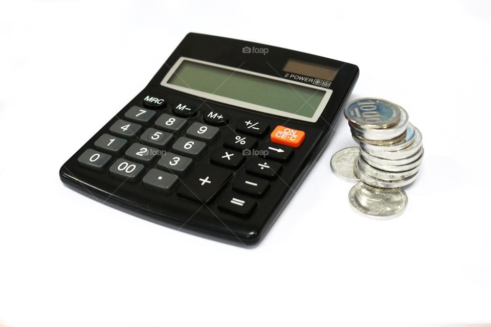 Photo of a calculator and coins on a white background