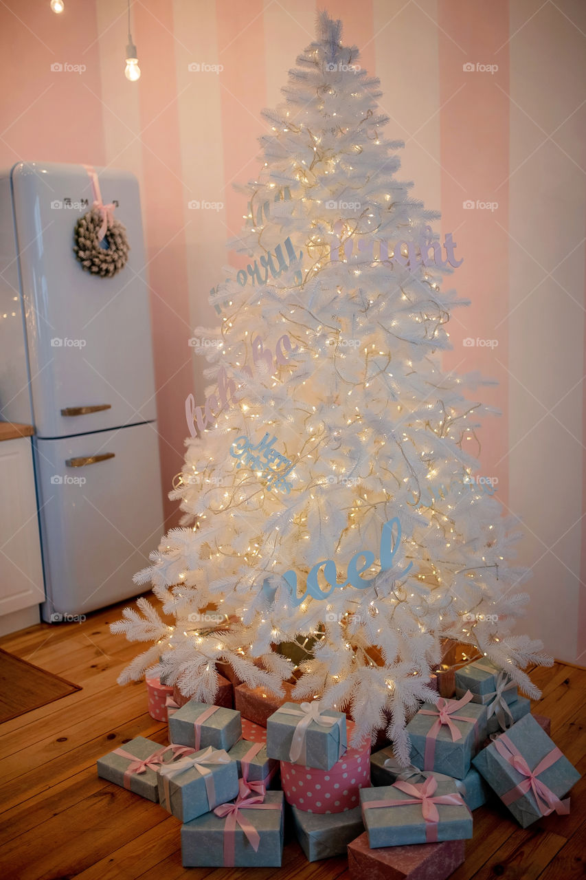 Festive winter cozy kitchen interior with garlands, decorations and gifts.  Christmas dinner at the decorated table.