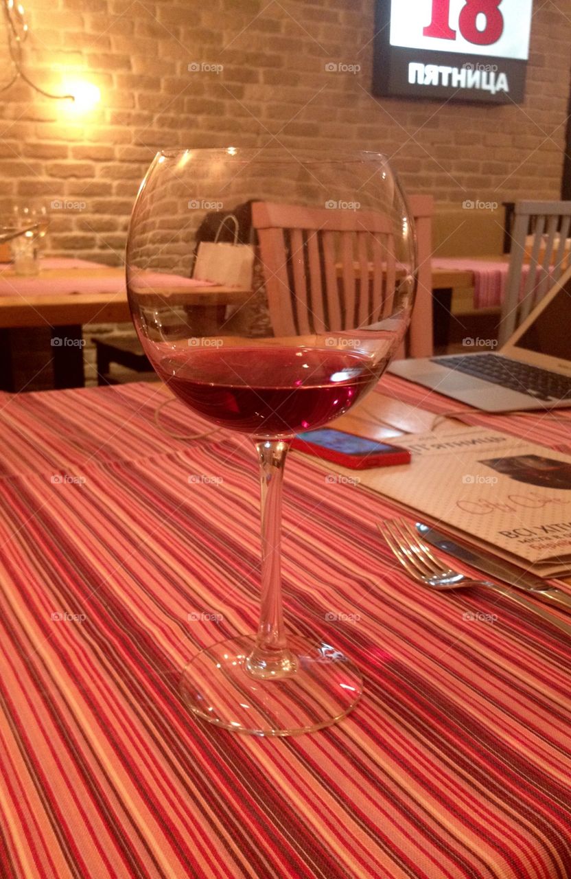 A glass of red wine on a table cloth in red stripes 