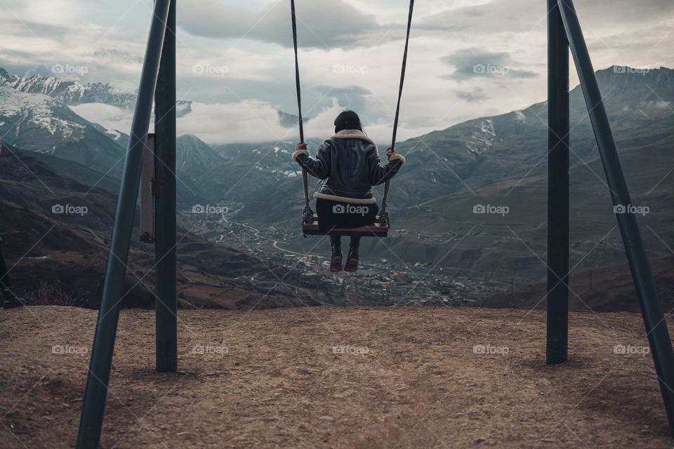 girl on a swing high in the mountains . back view.