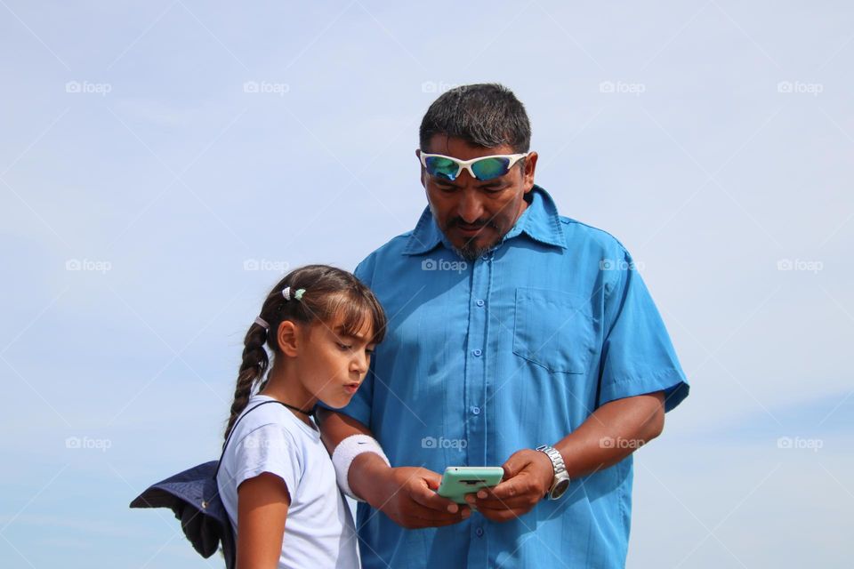 Father and daughter are using a smart phone to find directions