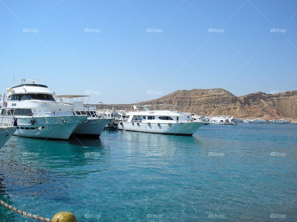 Harbor with yachts and sailing boats on a crystal clear water