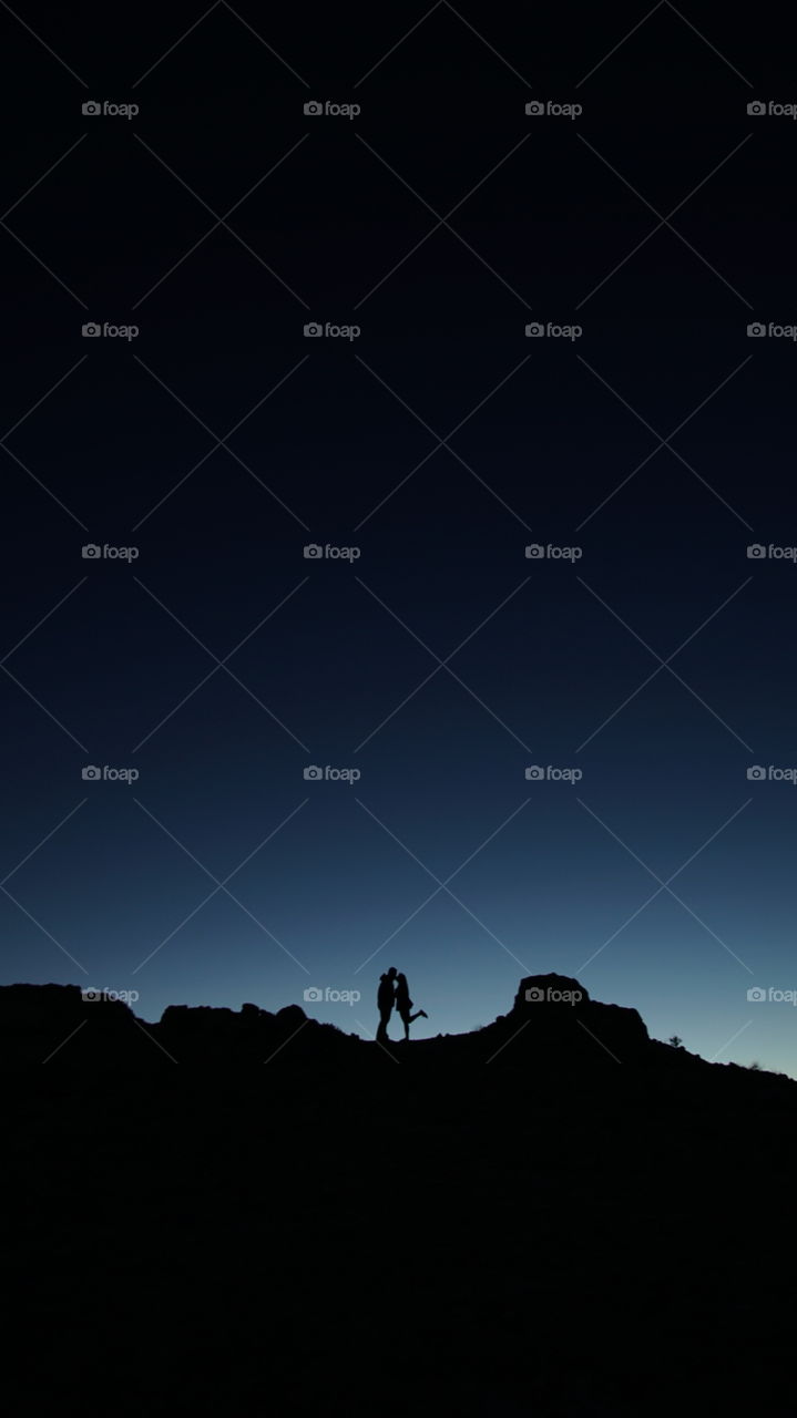 silhouette of a couple passionately kissing each other on top of a hill on a cold sunset