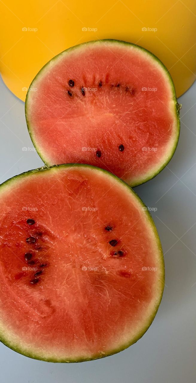 Red watermelon halves seen from above with yellow and pale blue background, pop colors 