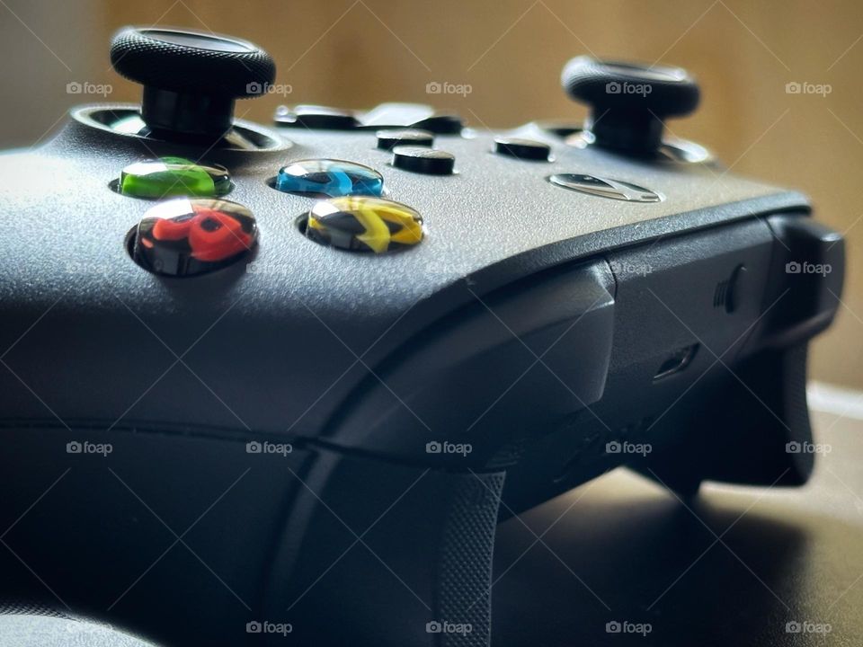 Close up of Xbox controller situated over a wood table while the morning light enters through the window.