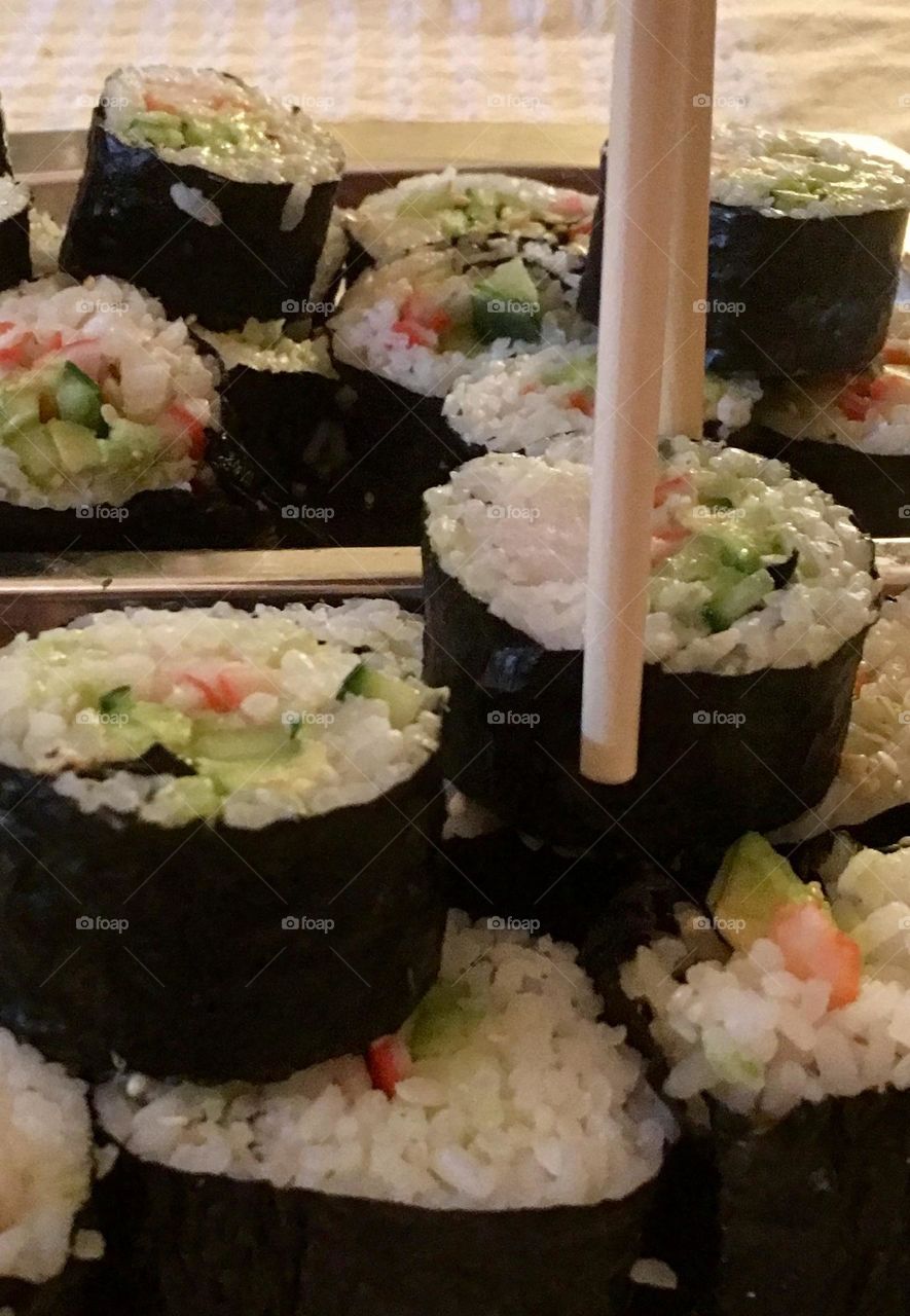 Japanese Maki sushi rolls, rolls being picked up with chopsticks, closeup, cuisine 