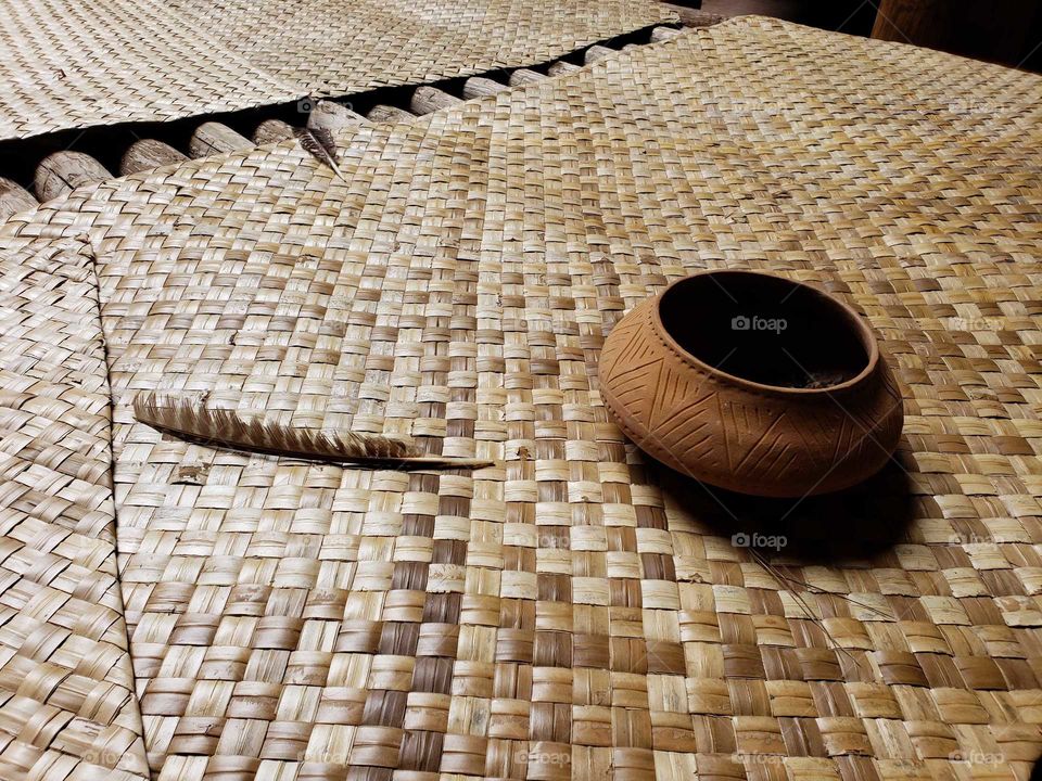 Native American bowl with feather on thatch mat