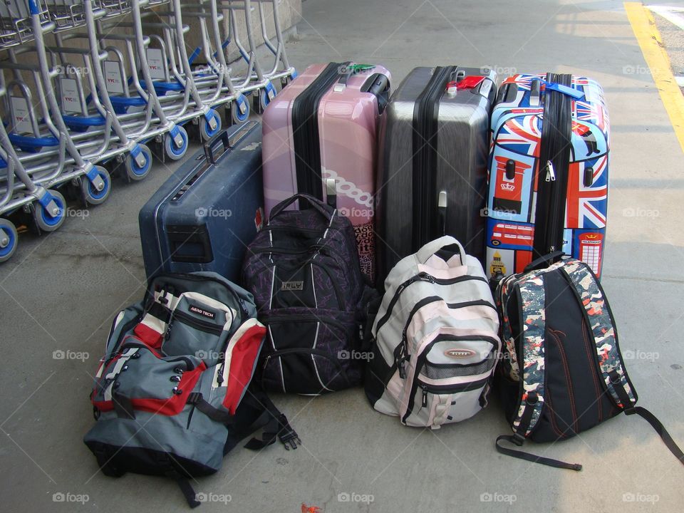 Suitcases and backpacks by the luggage carts,are all ready for travelling at the airport.