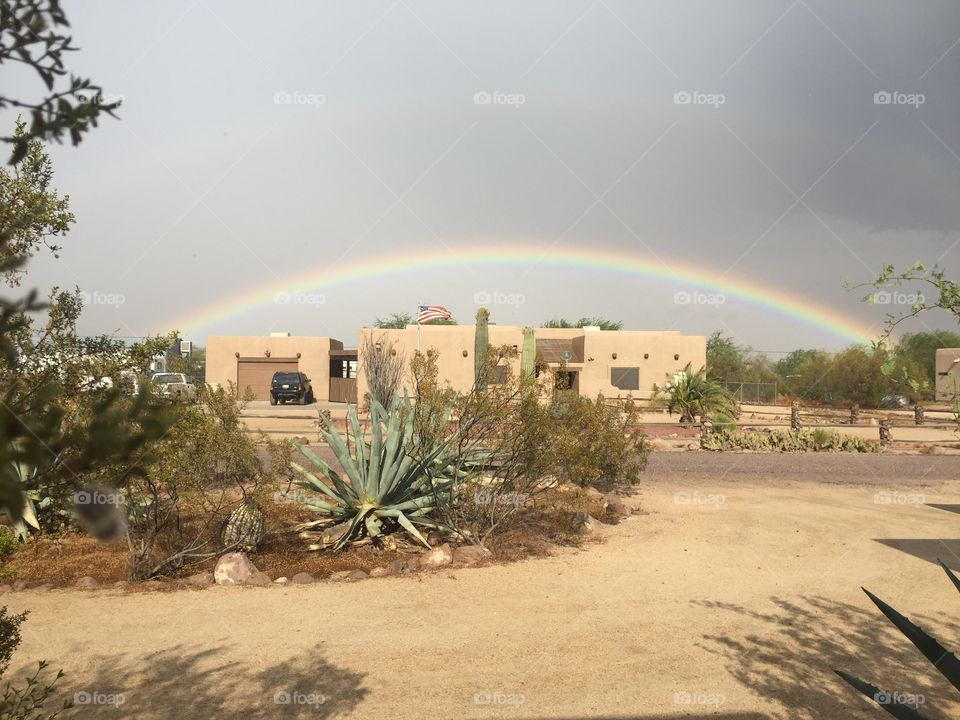 Desert territorial house with rainbow in background.