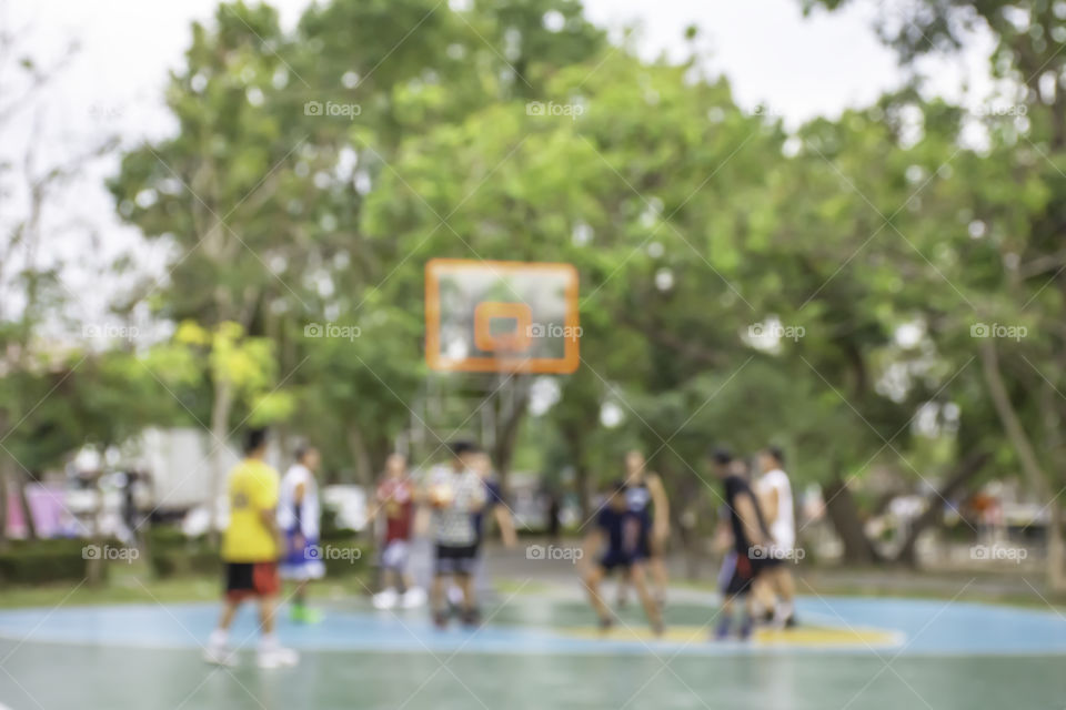 Blurry image of elderly men and teens playing basketball in the morning at BangYai Park , Nonthaburi in Thailand.