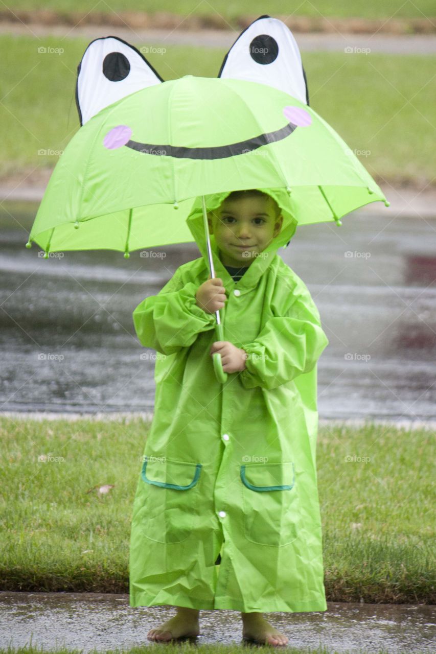 Smiling boy in raincoat holding umbrella