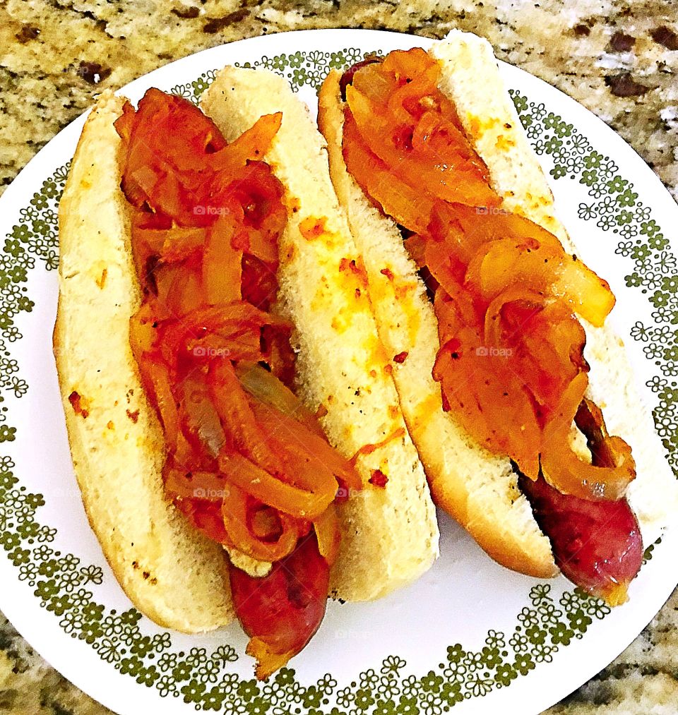 Footlong hotdogs with cooked onions and spicy tomato sauce and mustard 