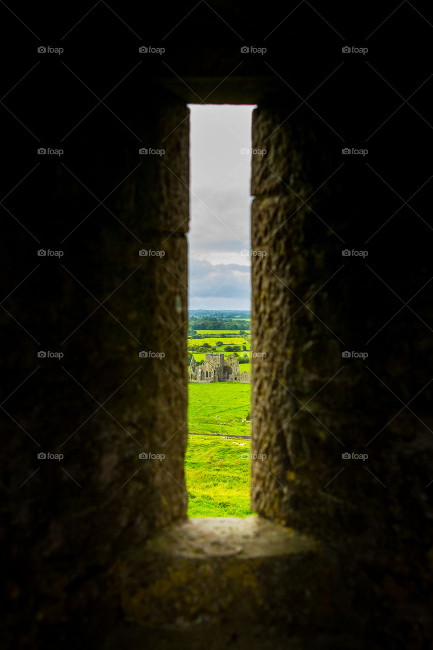 Window view of an ancient ruin in green fields