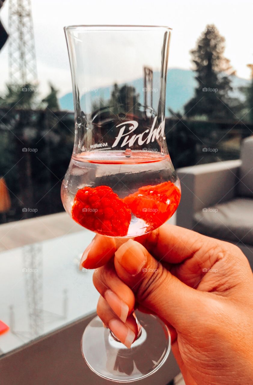 Hand is holding a glass of wine . raspberry in alcohol  drink