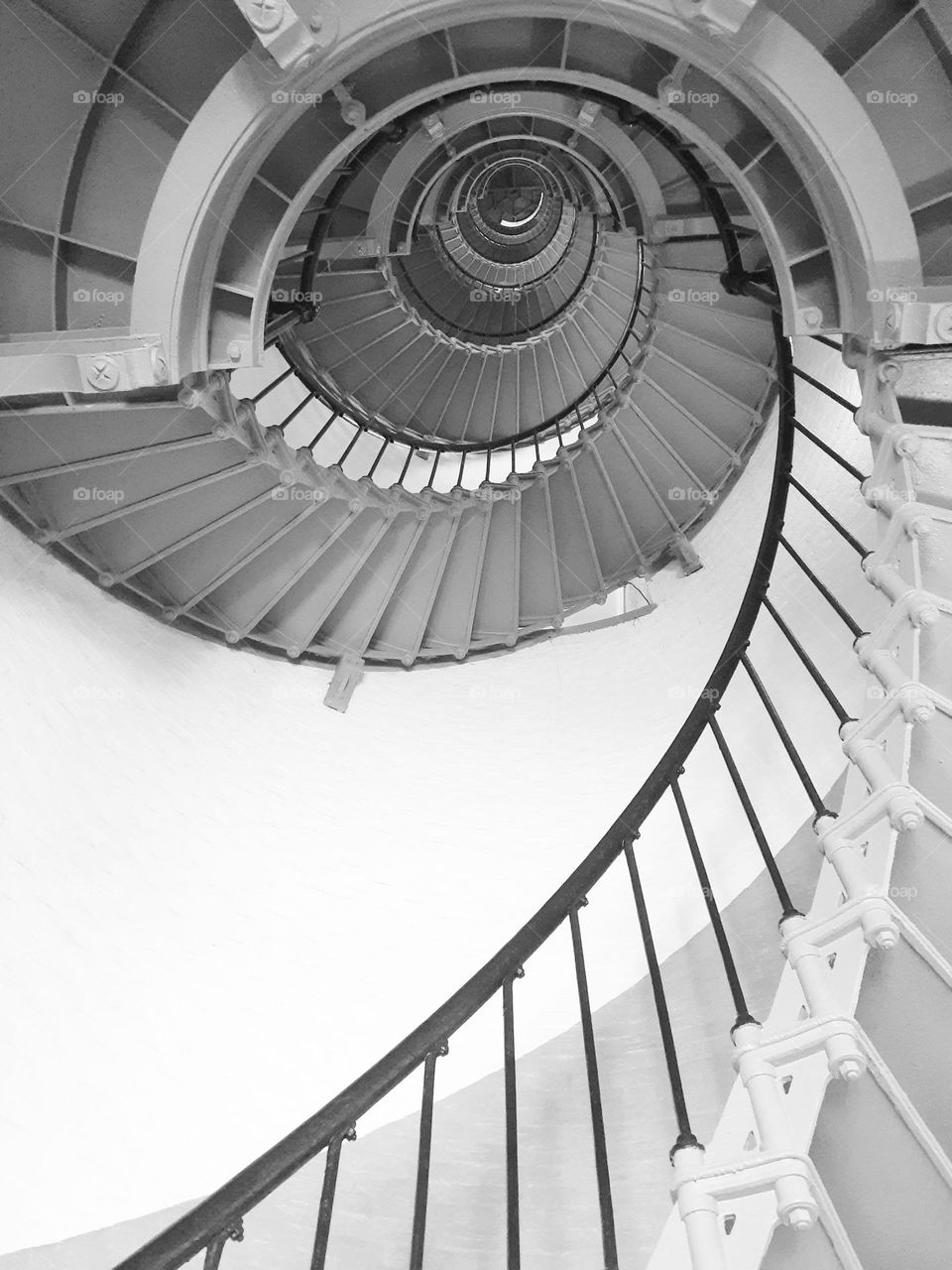 A black and white photo of the steep spiral staircase of the Ponce Inlet Lighthouse.