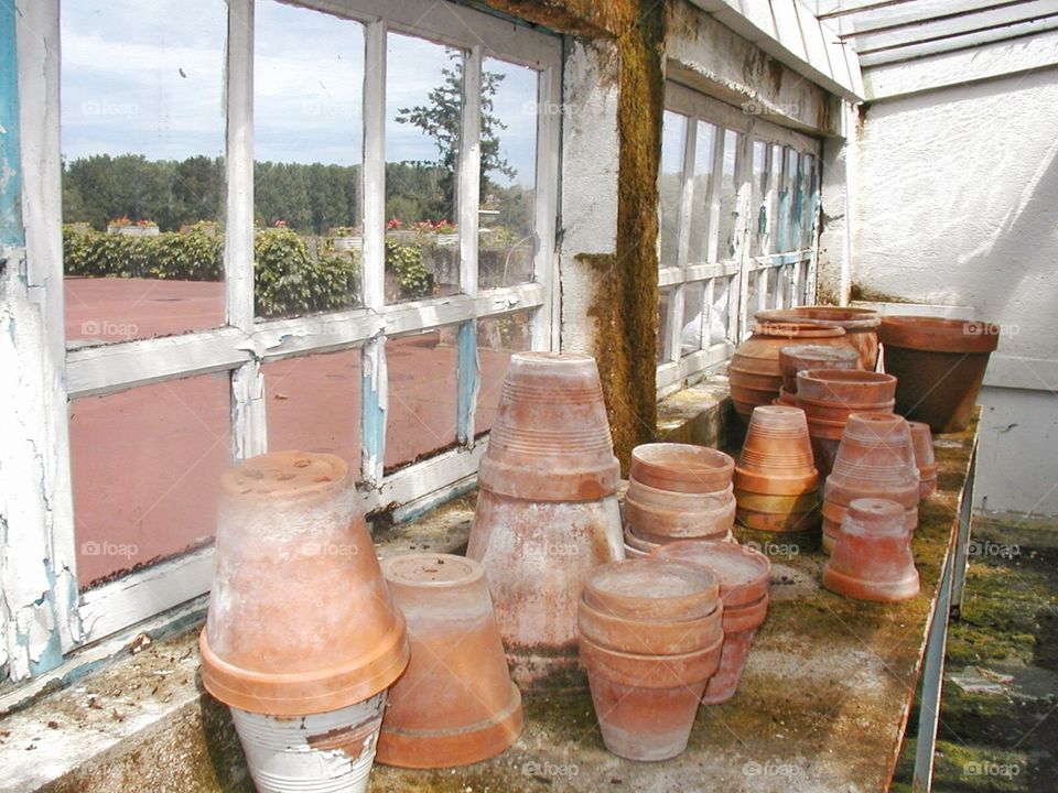 Potting shed. A The potting shed filled with clay pots with a view to the garden