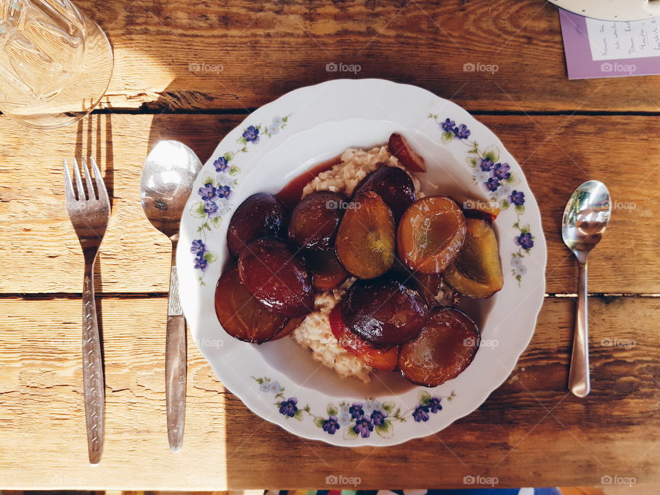 Porridge with plums. What else do you need to start your day right? Served on a nice painted porcellaine plate on a wooden table. Yummy.