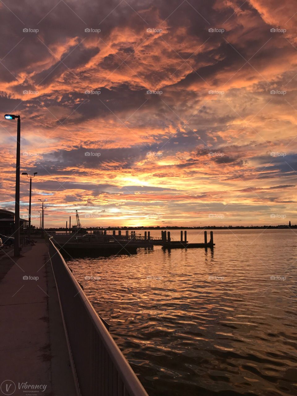A view of the fishing pier at sunset with the sunlight reflecting orange and yellow in the clouds