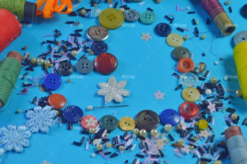 on a blue background there is a heart made of buttons and beads. theme of sewing and needlework.