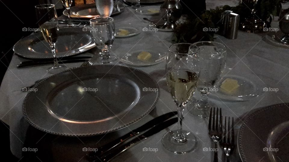 Formal Wedding dinner table setup silver plates silverware wine glasses water glasses butter dishes