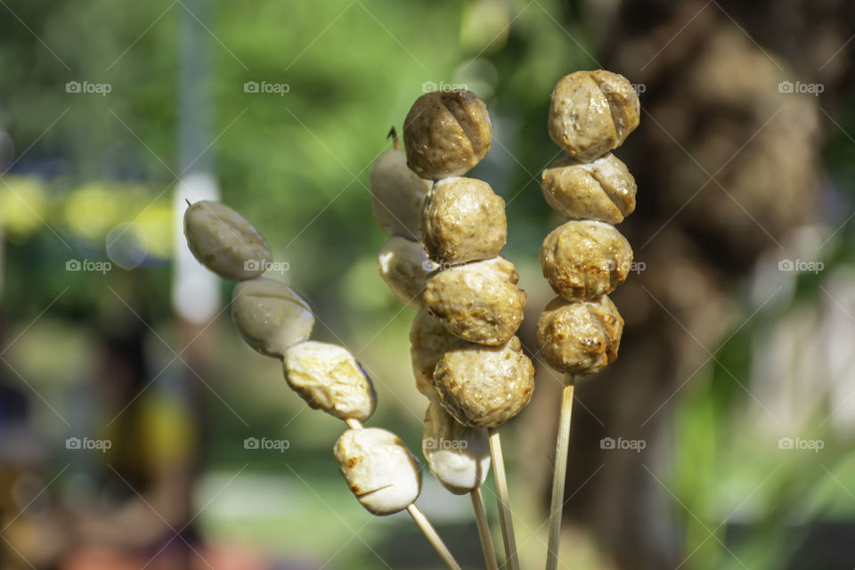 Hand holding Grilled pork and beef meatballs with seafood sauce  Background blurry Tree.